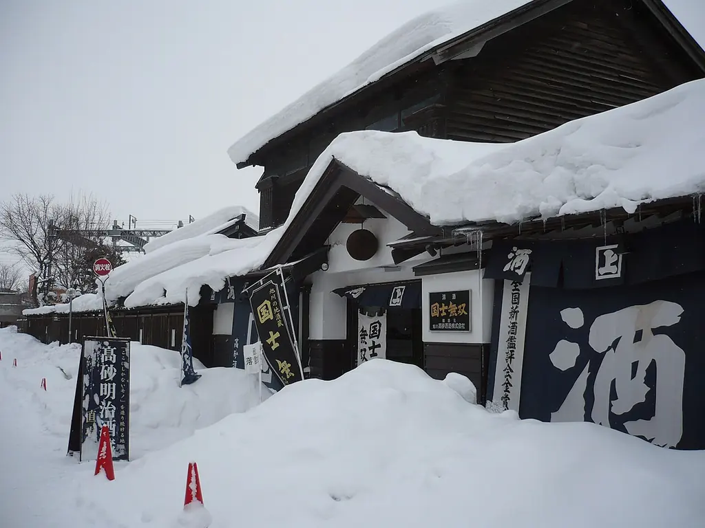 雪に埋もれた髙砂明治酒蔵と、大きな「酒」の幕
